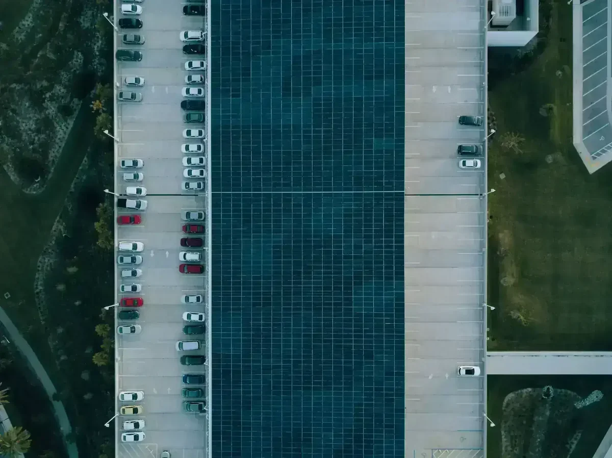 Visão superior de estacionamento com carros e vasta instalação de painéis solares