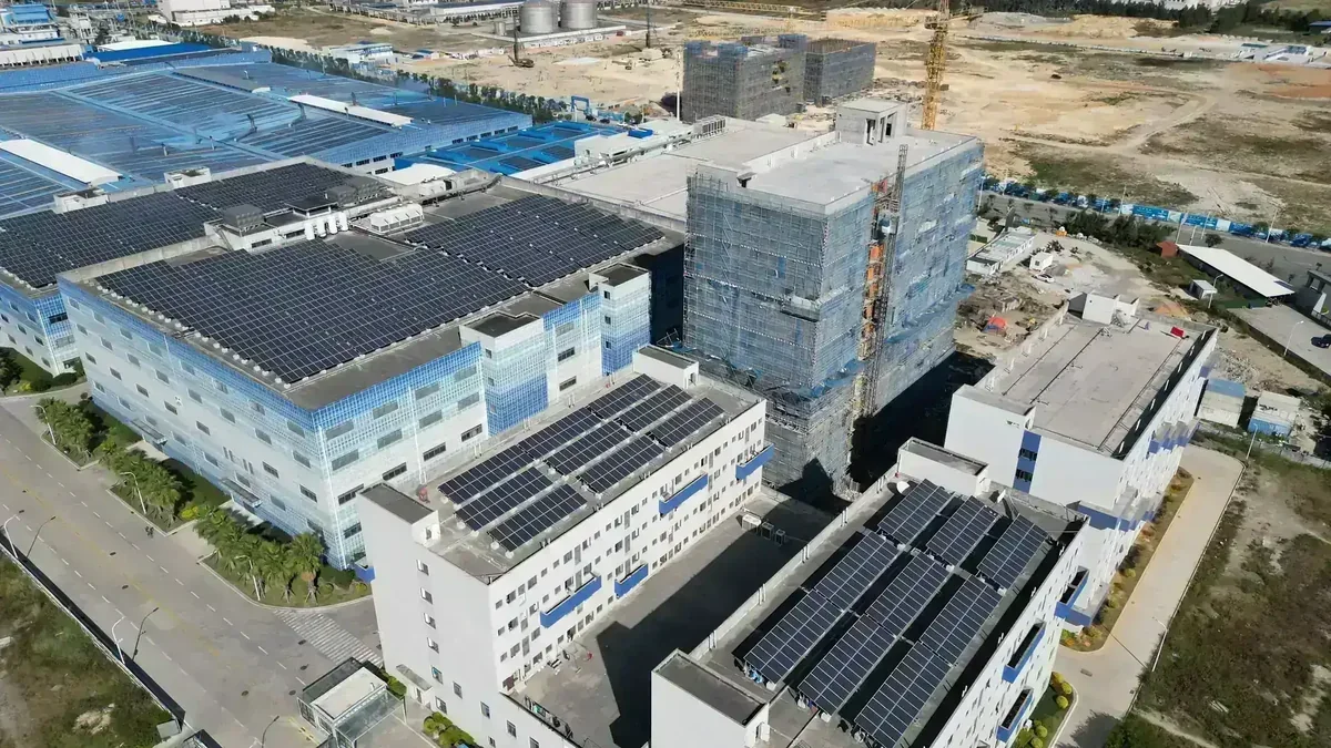 Vista aérea de complexo industrial com telhados cobertos por painéis solares e edifícios em construção