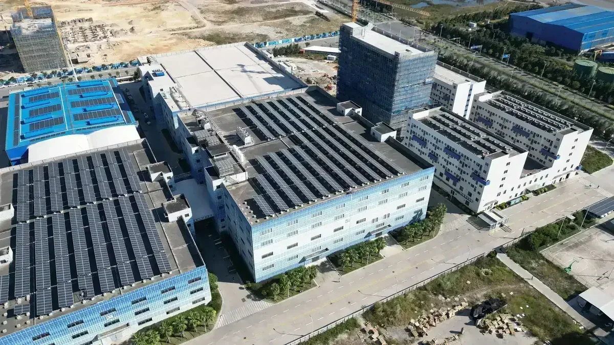 Vista aérea de complexo de edifícios industriais com painéis solares nos telhados e áreas de construção