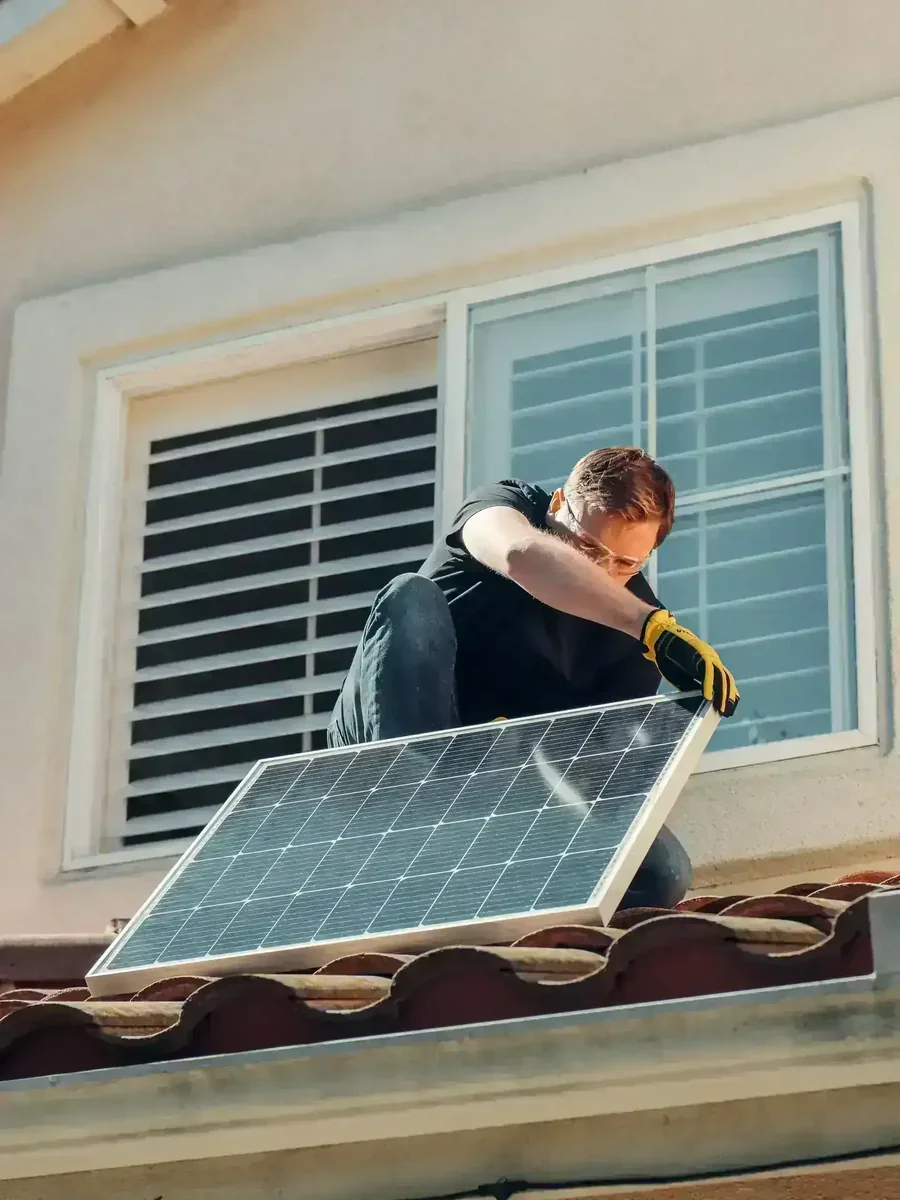 Instalador coloca painel fotovoltaico em telhado de casa com telhas de barro